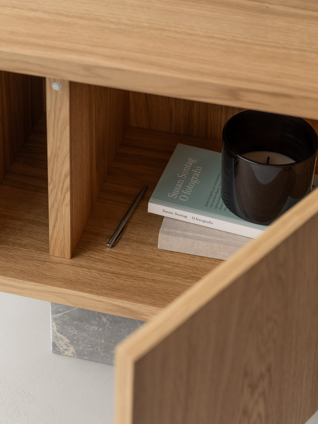 Open BLOCK Side Table in natural oak: push-to-open compartment with books, a candle and a pen, above a Fior di Bosco marble base.