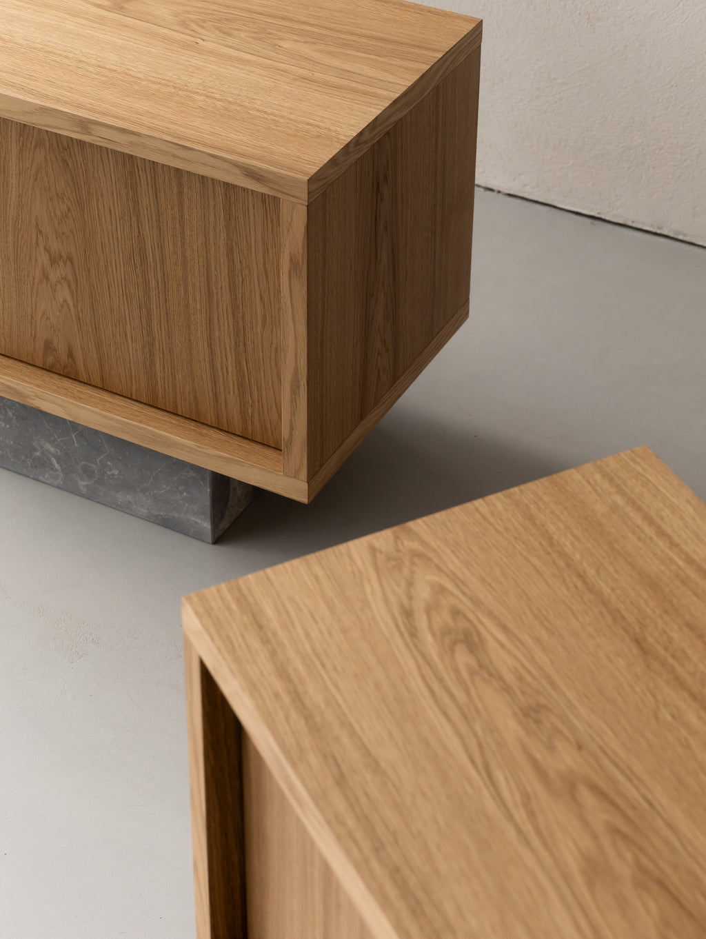 Top view of two BLOCK Side Tables in natural oak, one raised on a grey Fior di Bosco marble block.