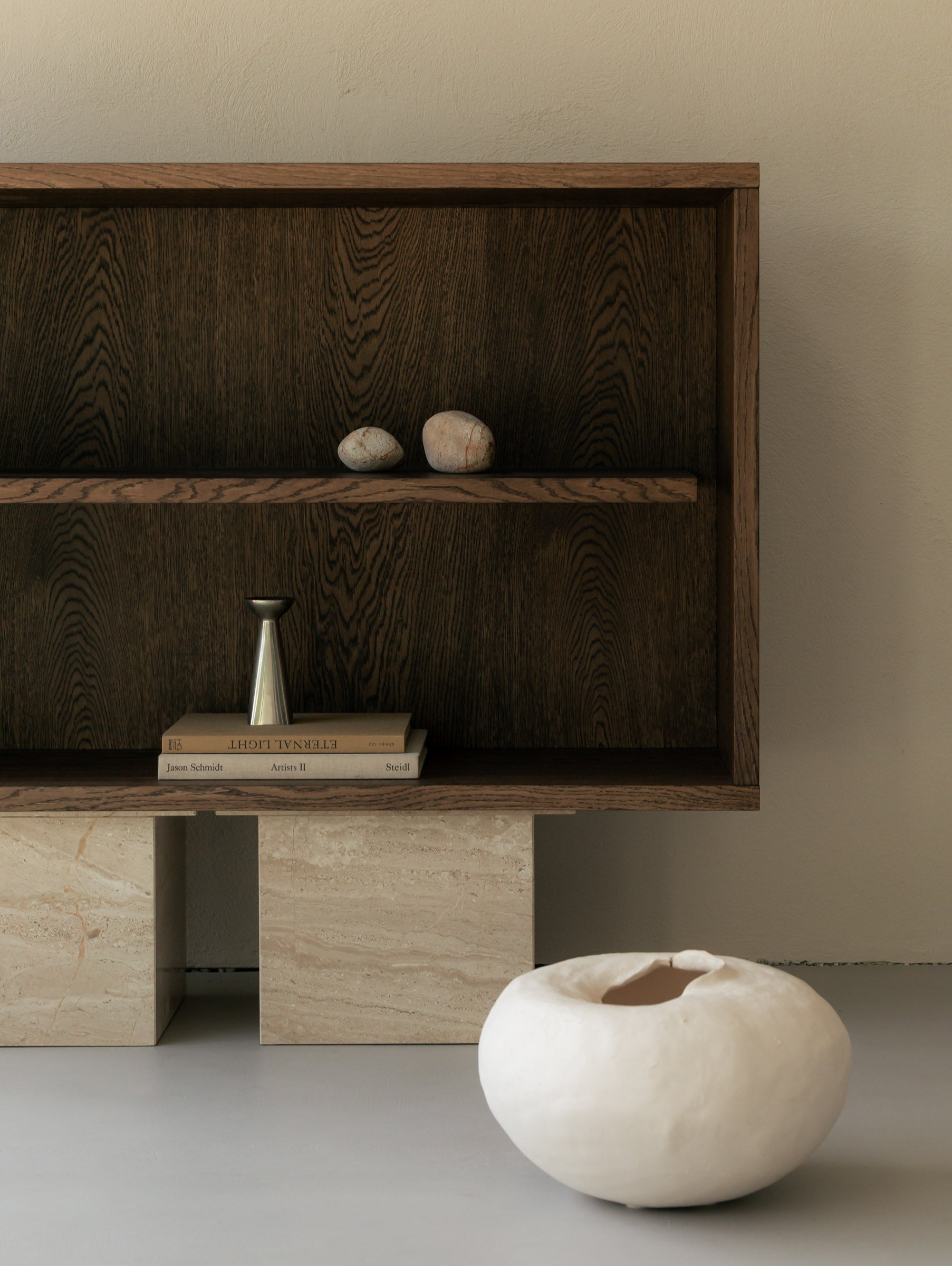 Un'common dark oak BLOCK Sideboard on Breccia marble block legs, styled with paired stones, a brass bud vase on stacked books, and an organic white ceramic bowl on the floor.