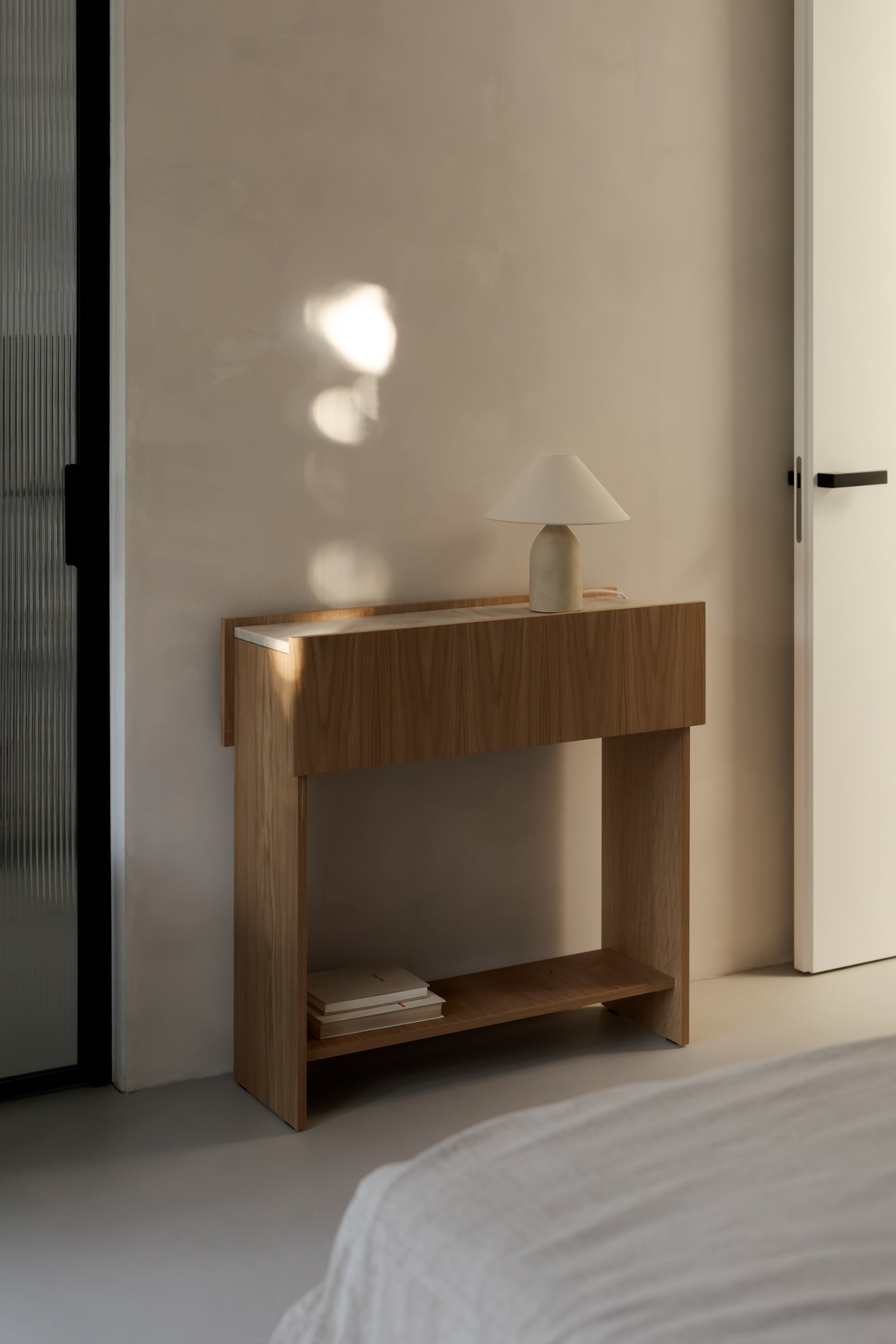 Minimalist oak console table with a natural Taj Mahal top styled in a warm neutral interior.
